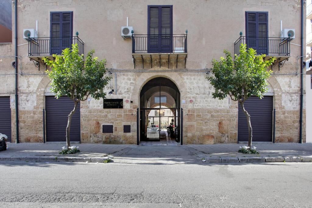 A building with a stone facade, two trees in front, and a metal gate.