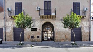 A building with a stone facade, two trees in front, and a metal gate.