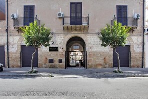 A building with a stone facade, two trees in front, and a metal gate. - Palazzo Corselli b&b (Bagheria)