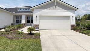 A single-story house with a garage, a small front yard with a tree, and a clear sky. - Cozy 2-bedroom cottage with AC in cool Jacksonville 55+ community in Mandarin (Jacksonville)