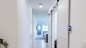 A hallway with white walls, a tiled floor, and a sliding door on the right. - Cozy 2-bedroom cottage with AC in cool Jacksonville 55+ community in Mandarin (Jacksonville)