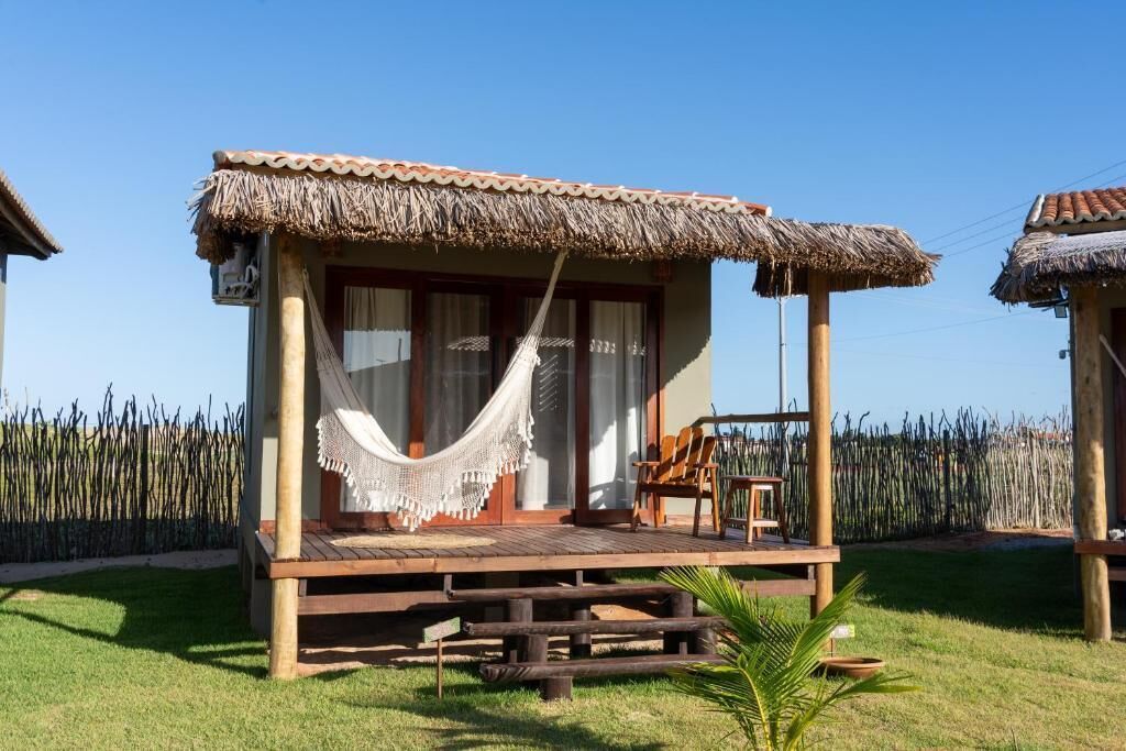 Una estructura de madera con techo de paja, una hamaca y un banco.