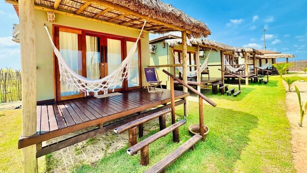 A wooden structure with a thatched roof, a hammock, and a deck. - Amigos do Vento Chalés e Kite Point (Touros)