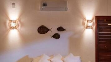 A bedroom with a bed, a red bedspread, wall-mounted lights, and a woven ceiling light fixture.