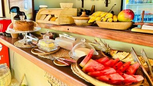 A buffet counter with various food items, a coffee machine, and a refrigerator stocked with beverages. - Amigos do Vento Chalés e Kite Point (Touros)