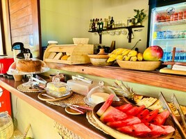 Un mostrador de buffet con diferentes alimentos, una máquina de café y un refrigerador lleno de bebidas.