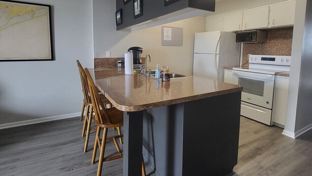 Une cuisine moderne dotée d’un îlot central, de meubles blancs et d’un coin repas avec des chaises en bois.