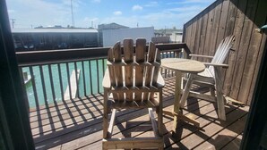 Une terrasse en bois avec une chaise et une table, d’où l’on peut admirer un plan d’eau et des bâtiments situés au loin.