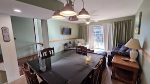A dining area with a large table, chairs, a chandelier, a television, and a sofa. - Waterfront Condo with Private Boat Slip and Community Swimming Pool (Port O`Connor)