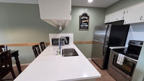 A kitchen with a central island, stainless steel appliances, and a sign indicating seafood cuisine. - Waterfront Condo with Private Boat Slip and Community Swimming Pool (Port O`Connor)
