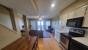 A kitchen with wooden flooring, a dining table, and a microwave.