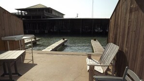 Un muelle de madera que se adentra en un cuerpo de agua, con un edificio al fondo.