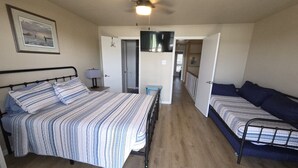 Una habitación con cama, sofá, ventilador de techo y televisión.