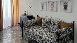 Um quarto com um sofá estampado, uma mesa pequena com um vaso e três obras de arte emolduradas na parede.