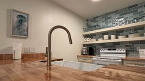 A modern kitchen with a marble countertop, stainless steel appliances, and a backsplash with blue tiles.