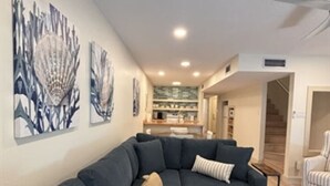 A modern living room with a sectional sofa, a striped armchair, and abstract wall art.
