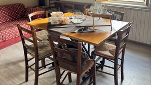 A dining area with a table, chairs, a red sofa, a lamp, and a painting on the wall. - Cozy Tuscan apartment near Siena, ideal for groups and families (Rosia)