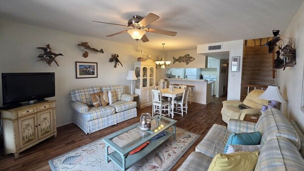 A living room with a television, two couches, a dining table, and a kitchen in the background.