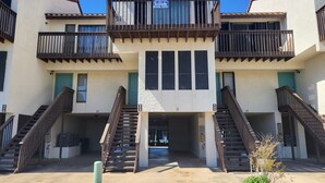 Un immeuble à deux étages, doté de balcons, d’un escalier central et d’une enseigne indiquant un service de location.