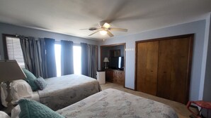 Une chambre d’hôtel avec deux lits, un ventilateur de plafond, une télévision, un bureau et une armoire.