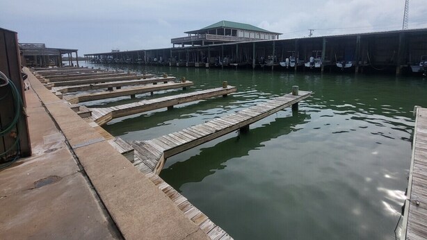 Une jetée au bord de l’eau, avec des passerelles en bois menant à un bâtiment doté d’un toit végétalisé.