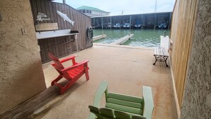 Un espace extérieur abrité avec un quai, un bâtiment en bois portant une enseigne, et deux fauteuils Adirondack.