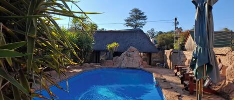 A swimming pool with a stone edge, surrounded by rocks and vegetation.