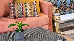 Un sofá con cojines estampados, una planta en maceta y una mesa de centro a rayas.