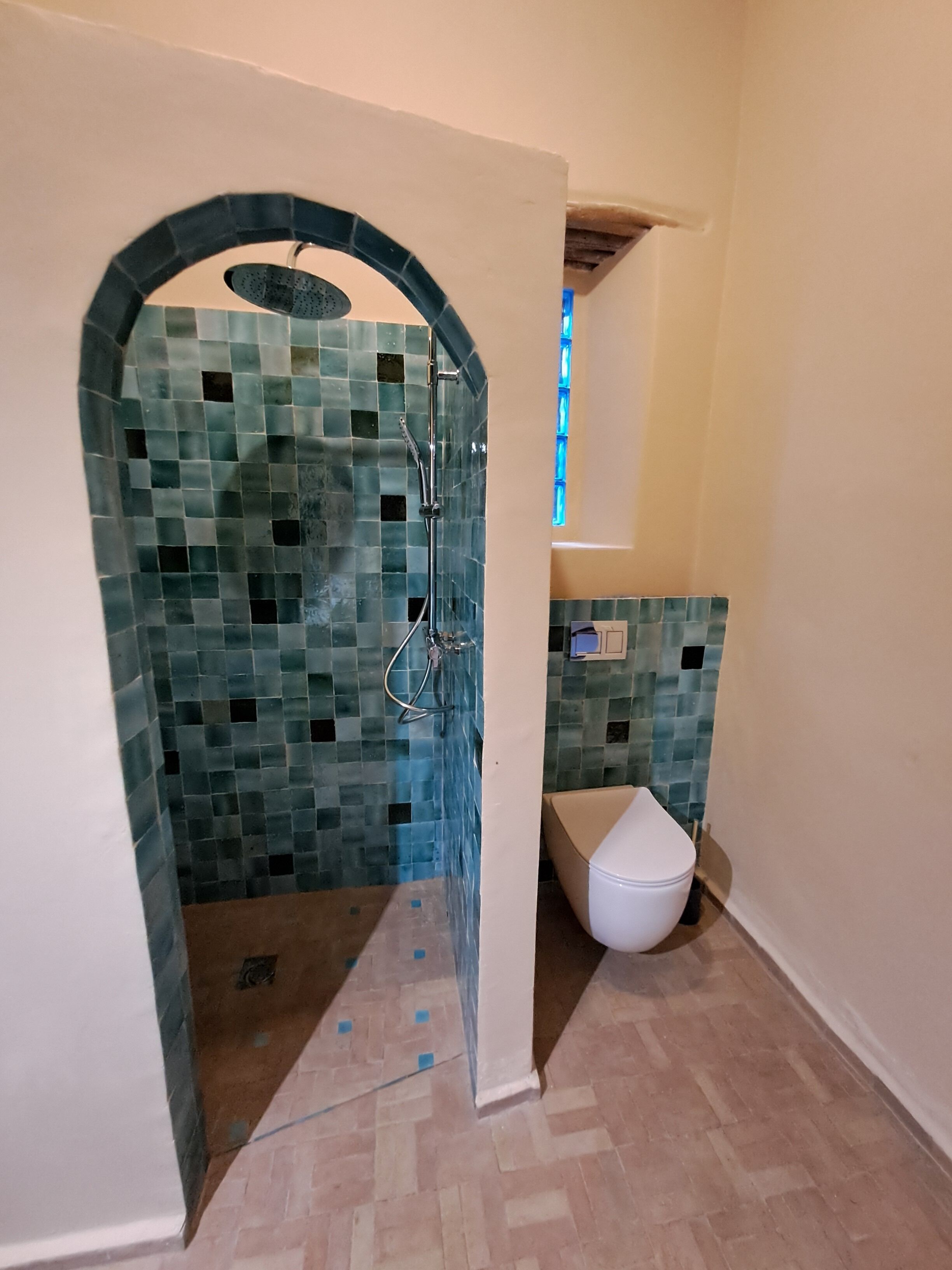 A bathroom with a shower, a toilet, and a tiled wall.