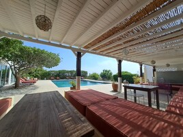 Una piscina al aire libre, sombrillas, sillones reclinables de piscina