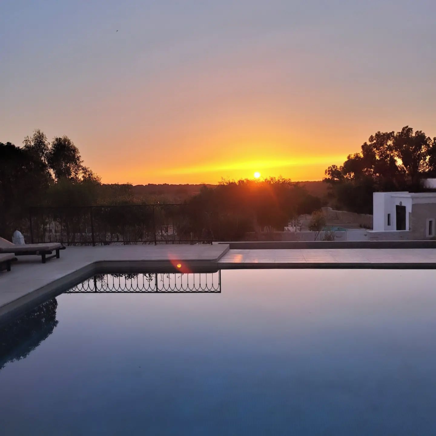 Klarer Himmel bei Sonnenuntergang, mit einem Pool, der den Himmel spiegelt.