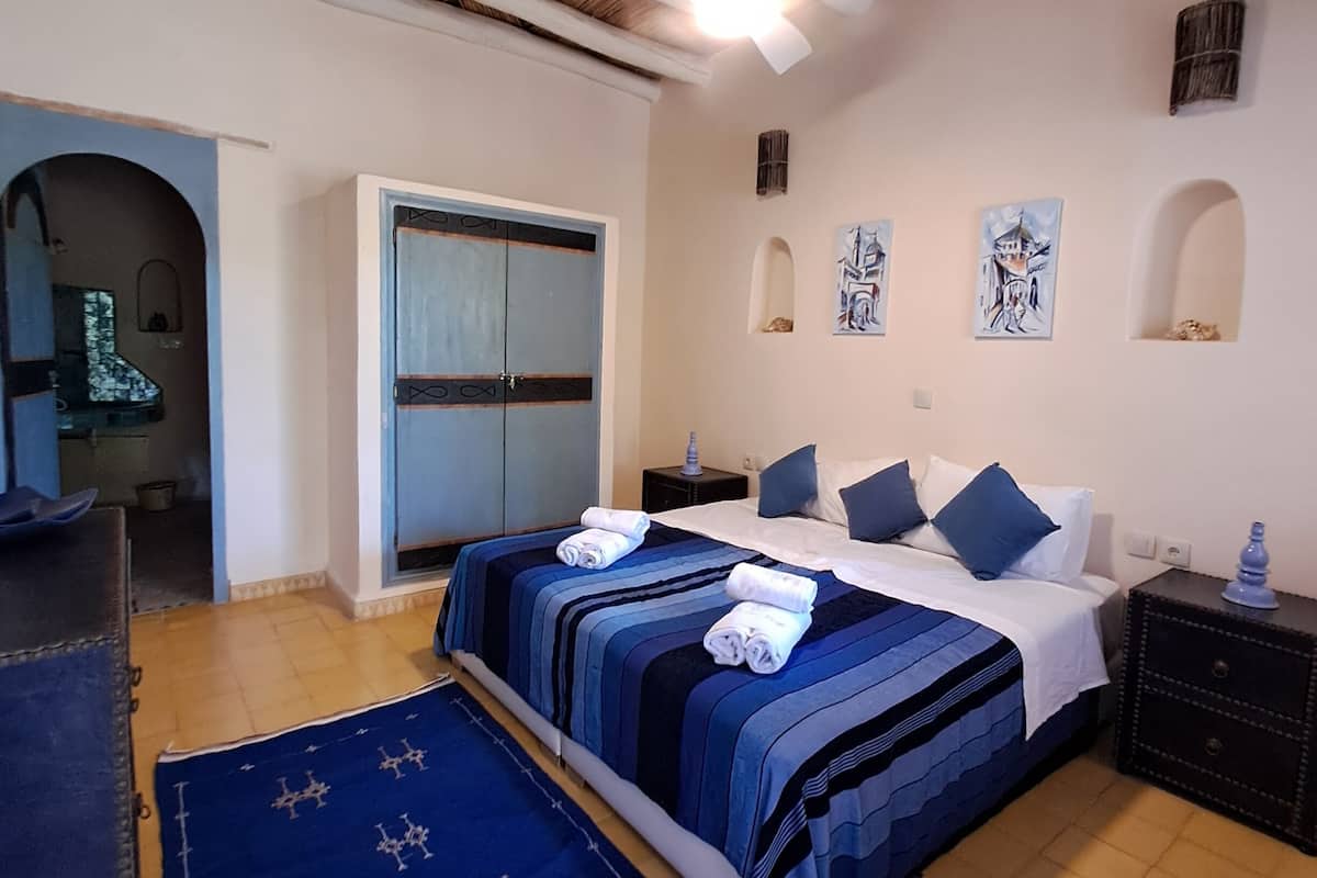 A bedroom with a bed, a nightstand, a wardrobe, and a blue rug.