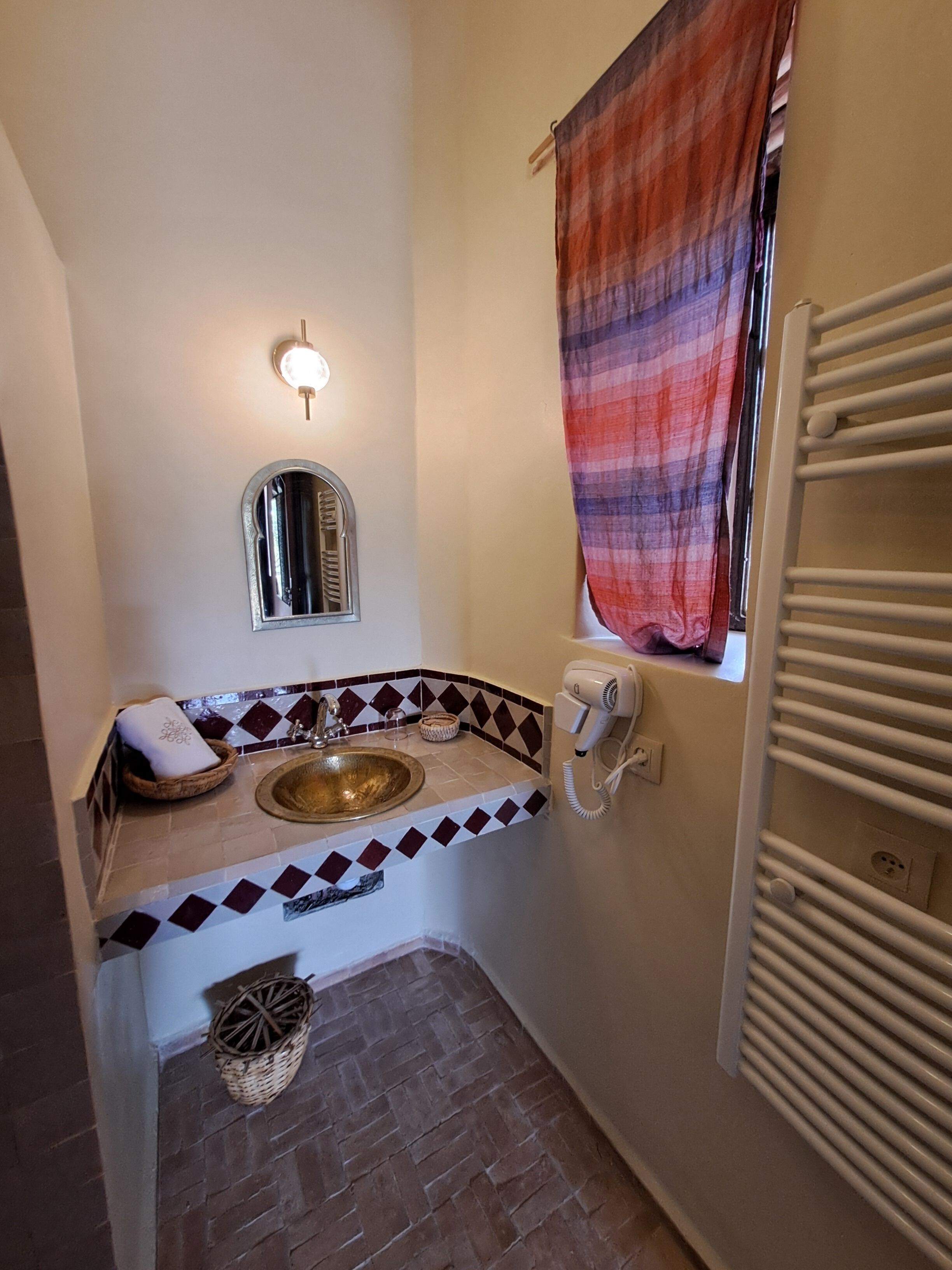 Ein Badezimmer mit Waschbecken, Spiegel, Handtuch und einem Fenster mit Vorhang.