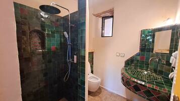 Et badeværelse med brusebad, toilet og håndvask.
