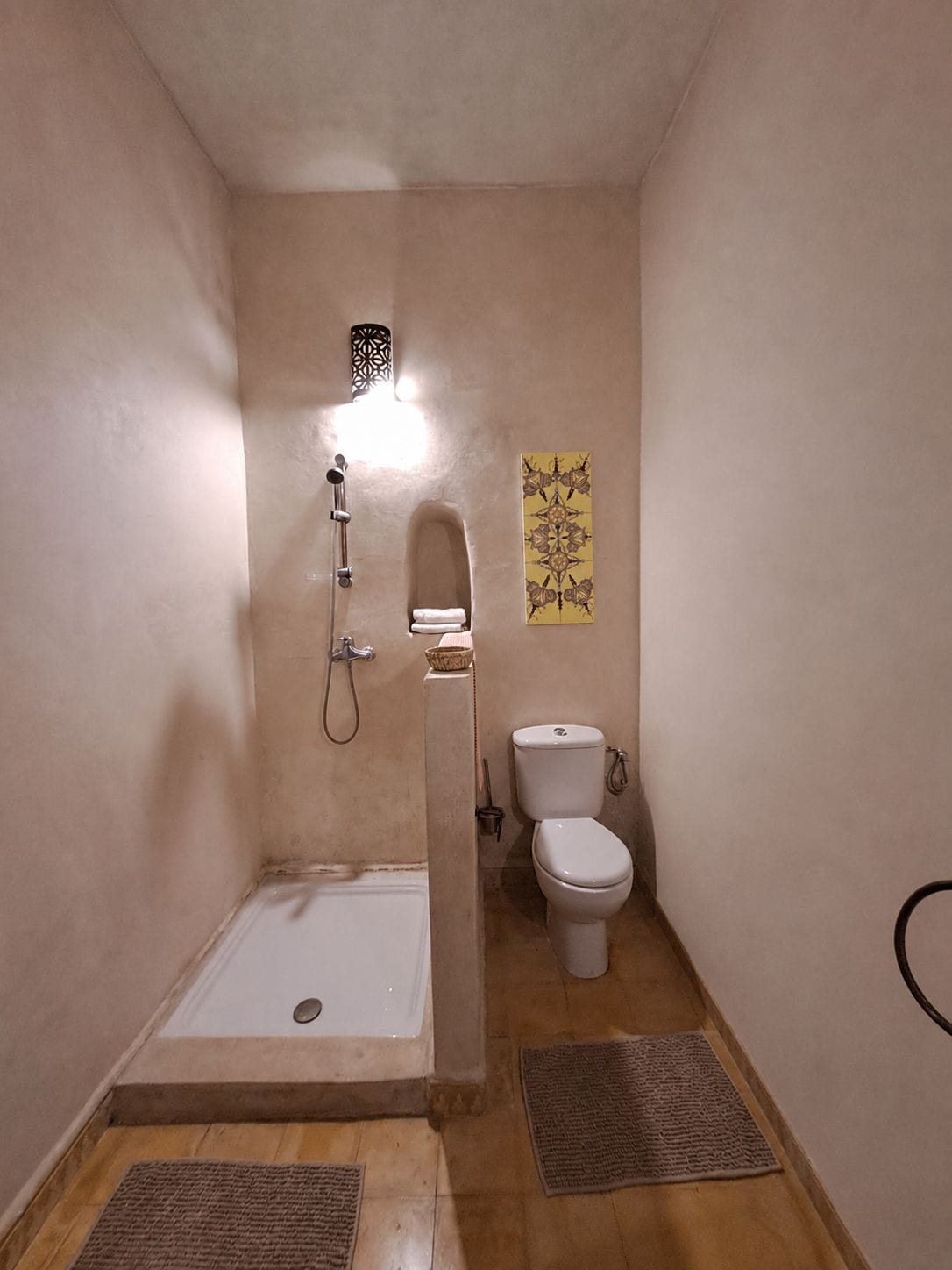 A small bathroom with a shower, toilet, and a towel rack.