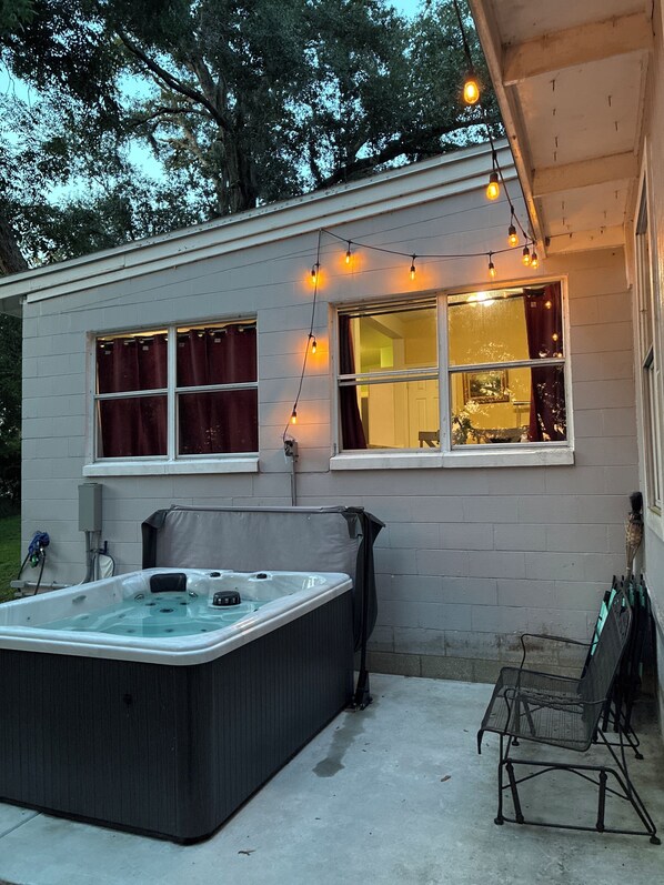 Ett hus med en bubbelpool, en möblerad uteplats och ljusslingor.