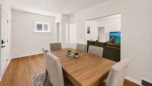 A dining room with a wooden table, four chairs, and a sofa. - Willow & Mist - Gorgeous 3-bedroom house minutes from Niagara Falls attractions (Niagara Falls)