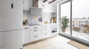 A modern kitchen with white cabinets, a built-in oven, and a large window overlooking a patio area.