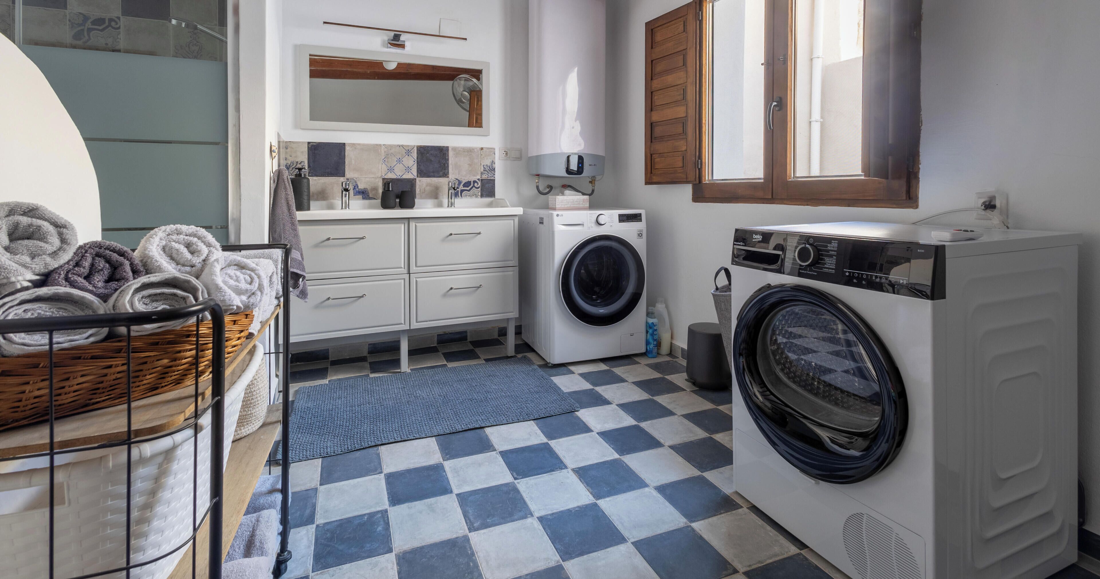 Een wasruimte met een wasmachine, droger en een mand vol opgevouwen handdoeken.