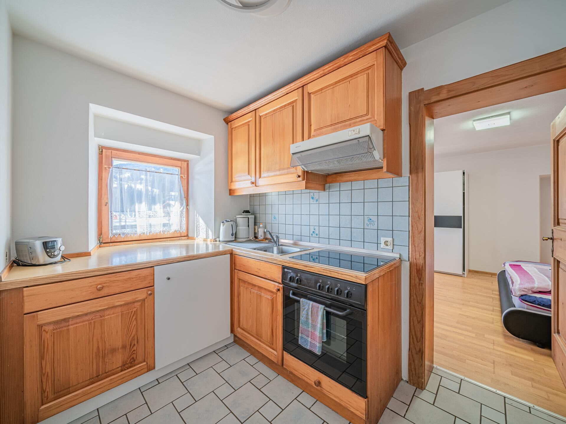 A kitchen with wooden cabinets, a stove, a window, and a tiled backsplash.