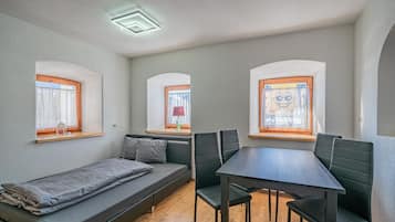 Habitación compacta con sofá, mesa de comedor y tres ventanas.