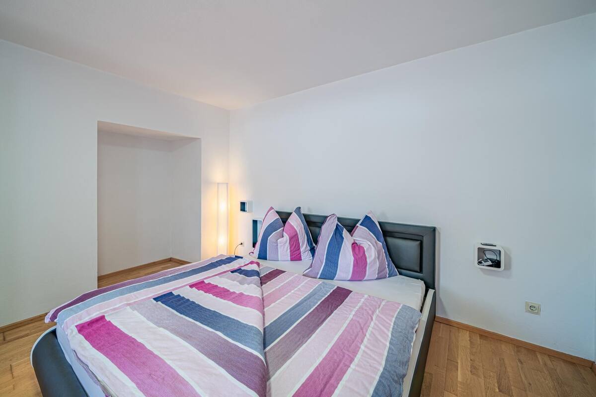 Ein Schlafzimmer mit einem Bett, einer Nachttischlampe und einer Steckdose.