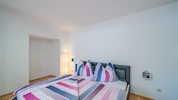 Un dormitorio con cama, lámpara de noche y toma de corriente.