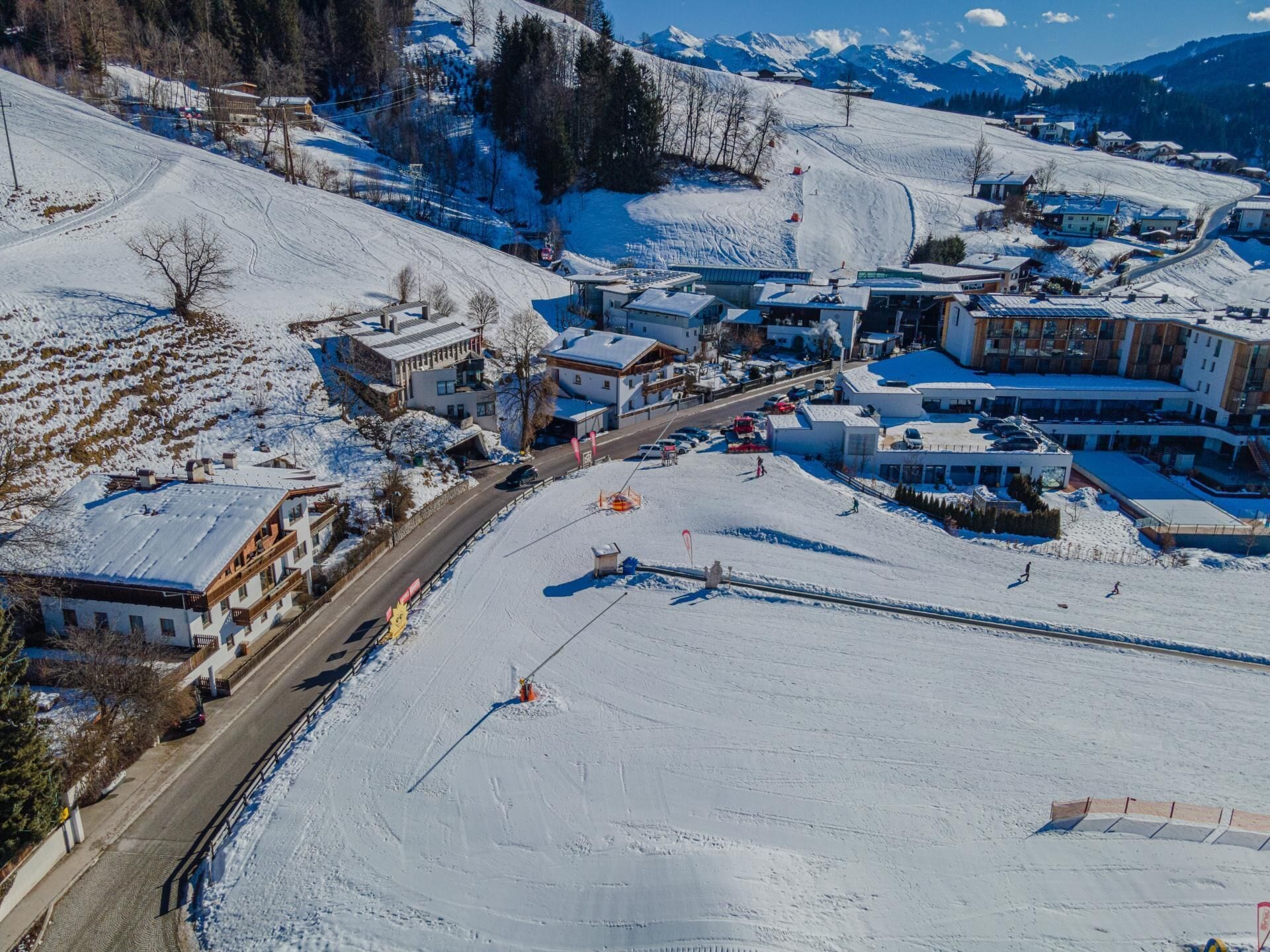 A snow-covered town with buildings, a ski slope, and a road.
