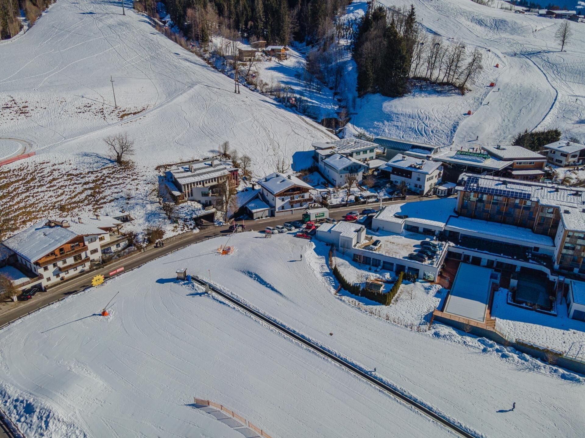 A snow-covered ski resort with buildings, roads, and ski tracks.