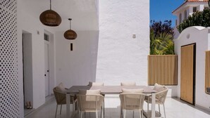 A patio with a white table and wicker chairs, a white wall, and a wooden fence. - Modern 3 bed apt, walking distance to Puerto Banus (Marbella)