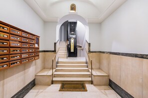Eine Treppe mit einem Holzsesselregal links, einem Marmorboden und einem kleinen gerahmten Bild oben.