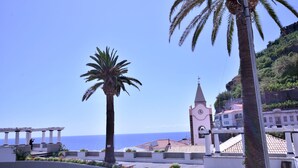 Un poble costaner amb una església destacada, palmeres i una vista clara del mar.