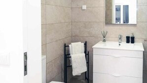 Un bany modern amb un lavabo blanc, un mirall i un escurapulides.