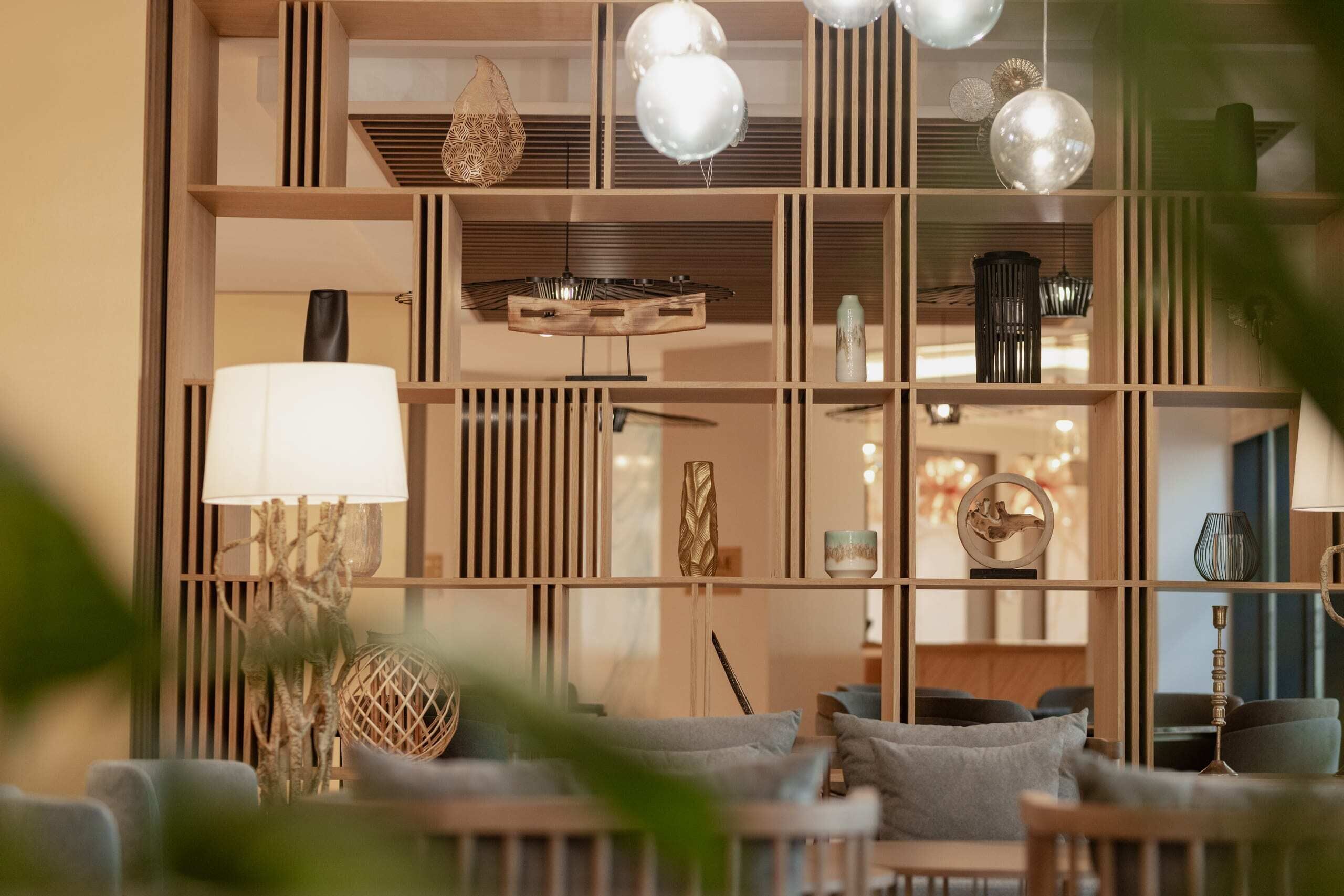 Un interior moderno con un separador de madera, una lámpara esférica colgante y una lámpara.
